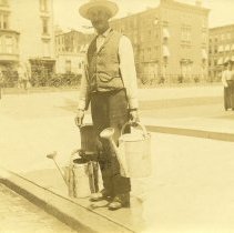E. Alice Austen, Street cleaner with watering pots, 1895.