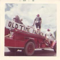 Several Eagle firemen ride on a fire truck sporting the banner  . . .