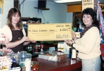 Two women hold a check from a Go-Fer store for Eagle Library 1986