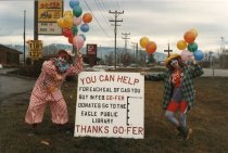 Two people dressed as clowns pose with fundraising sign 1986