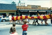 Children under a yellow and red fabric walk on State St. 1986