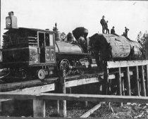 Fort Bragg RR locomotive #3 pushing large logs on bob-cars on low trestle.