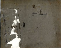 Joe Lane, Comptche, outside his rose-covered house, holding a rifle.