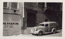 Black and white photograph of Kress store back alley with car visible