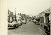 Black and white photograph ofstreet view showing new neon sign, taken in Se