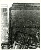 Black and white photograph depicting exterior fire damage with view of scaf