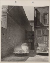 Black and white photograph of Kress store back alley with the parking lot v