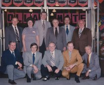 Color photograph of a group of men posing in front of a Dollar Dart store