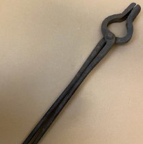 Flat bar tong used in metalworking.