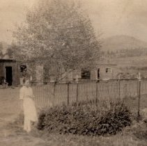 Woman in yard at ranch house.