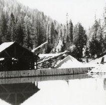 A pond with a lumber mill in the background ca 1945