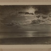 Moonlight on the water and beach moon obscured by clouds-small surf.