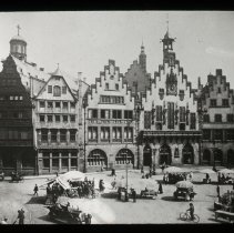Image of five buildings. Town square. Many people on the street.