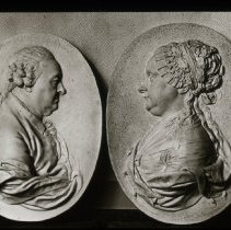 Two "plate" like objects with prints of bust of a man and woman.