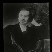 Man looking off in the distance. Tree/Plant next to him. Seems to be holdin