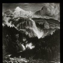View of Mountain top. Waterfall in foreground. One man in the middle of the