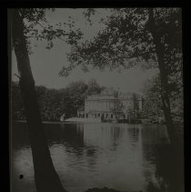 Viewpoint behind a couple trees looking to a huge building maybe a mansion.