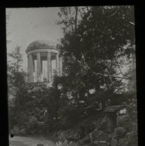 Walkway on the side of a lake. Pavillion with domed ceiling in background.