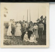 Thirteen men, women and children posed outdoors