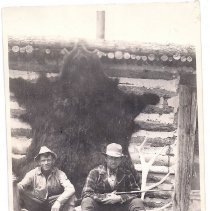 Two men with a large bear fur