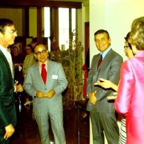 Five adults standing in a circle talking.