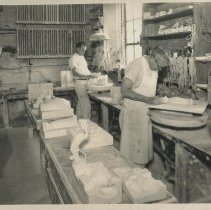 Two Cowan employees removing unfired pieces from plaster molds.