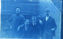 Four Young Men Posing in Front of Wooden Building