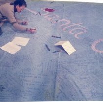 Man writes on large blue quilt