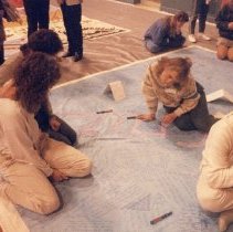 Group of people sit on large blue quilt