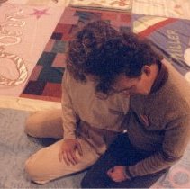 Two people embrace on the memorial quilt