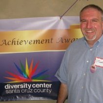 Stuart poses in front of the poster for the event.