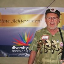 Dan Dickmeyer poses in front of the Lifetime Achievement Award poster.