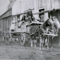 Workers atop a horse drawn wagon.