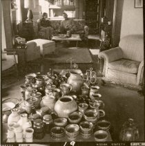 Individuals sit on couch with pottery in the foreground.