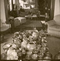 Individuals sit in the background with a display of pottery in the foregrou