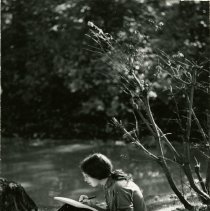 Female student Studying by Pond