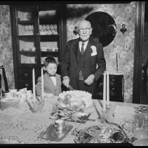 Elderly man cutting cake, boy looking on