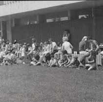 People sit along benches in front of Haverhill Public Library, 1973
