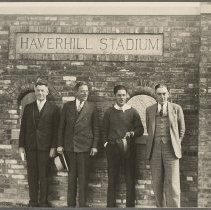 Four men stand in front of Haverhill Stadium sign, 1935