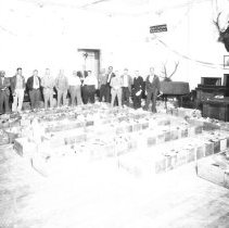 Members of the Elks Club standing behind rows of boxes packed with food. "T