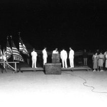 Group of people on a outdoor stage holding flags at the Elks Club Flag Day