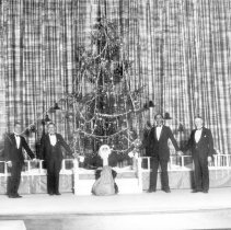 Elks Club Christmas tree. Santa Claus is seated in front of it holding hand