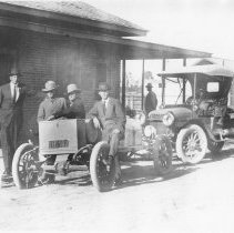 Four men, with auto and truck, in front of the United States Immigration Of