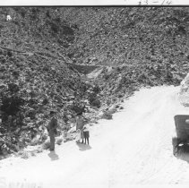 Mt. Springs Grade. Man and woman, with children standing on road.