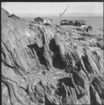 Mullet Island - Rocky terrain with abandoned buildings in background.