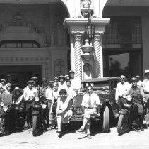 Group of people posing with a car parked in front of the Barbara Worth Hote