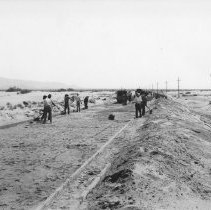 Work crew froming new highway through sand dunes.