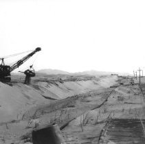 Dragline digging road for new highway going through sand dunes. Plank road