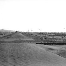 Distance view of dragline digging new highway road through sand dunes.