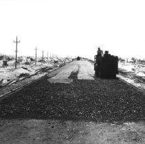Steam roller rolling new paving material on highway through Sand Dunes.